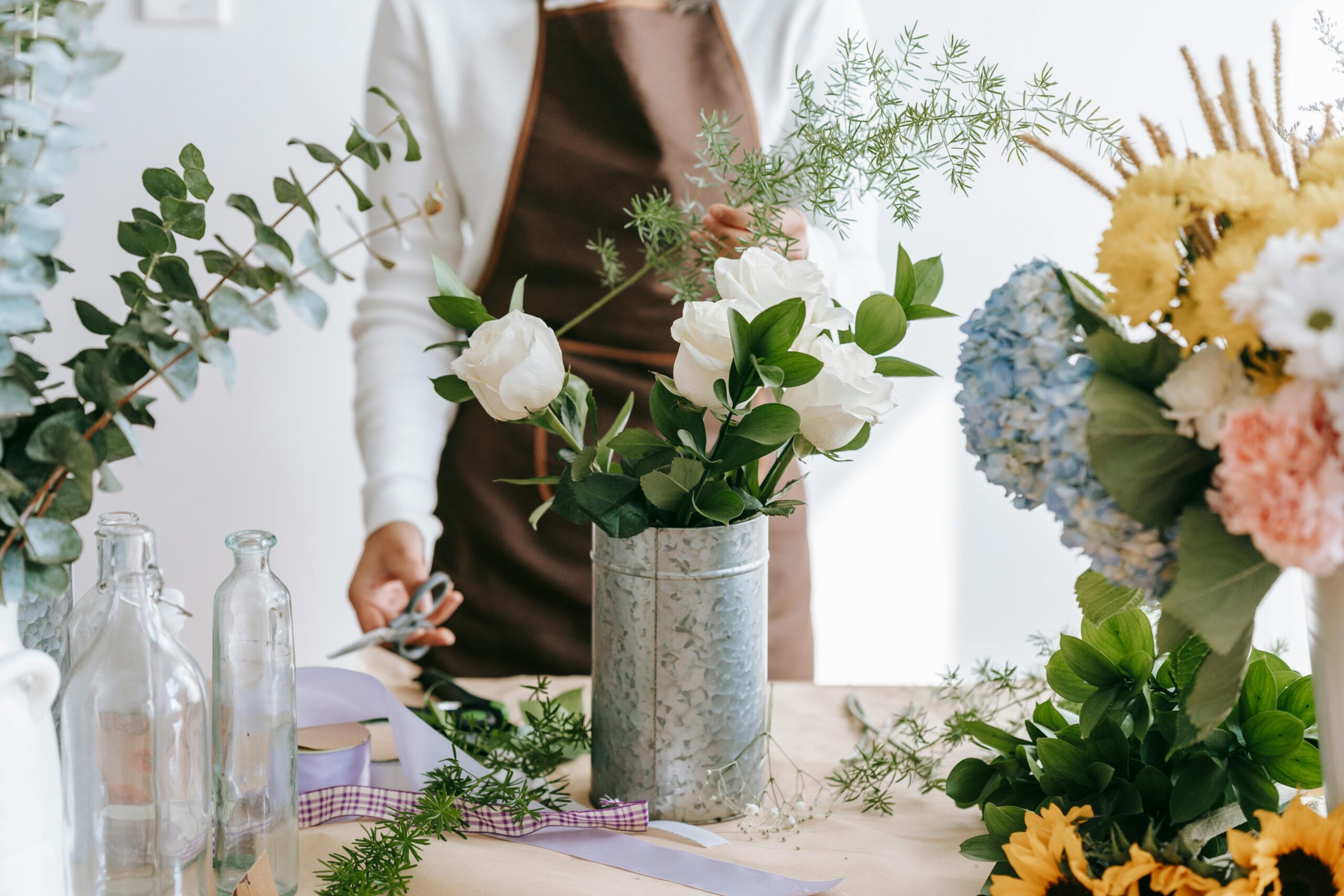 Florist arranges a colorful bouquet in a bright indoor workspace, showcasing floral artistry.